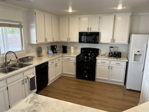A modern kitchen with white cabinets, a black stove, a microwave, and a dishwasher.