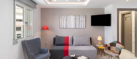 A modern living room with a sofa, two armchairs, a coffee table, and a flat-screen TV mounted on the wall.