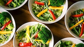 Multiple bowls of salad with various vegetables.