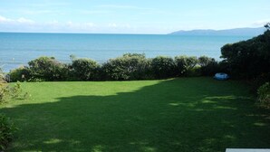A grassy yard with a view of the sea and distant mountains. - Absolute beachfront Raumati (Paraparaumu)