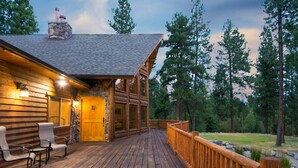 A log cabin with a wooden deck, stone fireplace, and a stone chimney. - Pineview Lodge (Hamilton)
