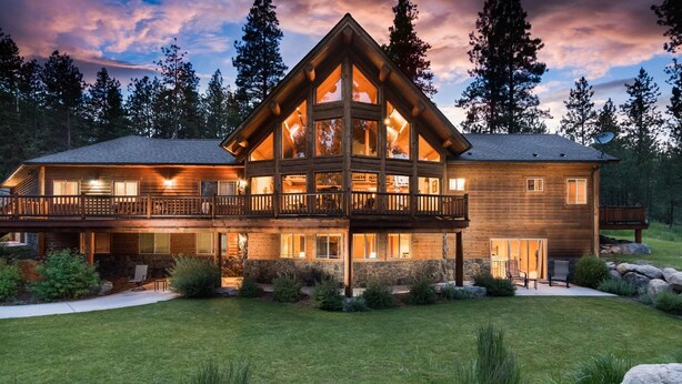 A large log cabin with a balcony, surrounded by a well-maintained lawn and trees. - Pineview Lodge (Hamilton)