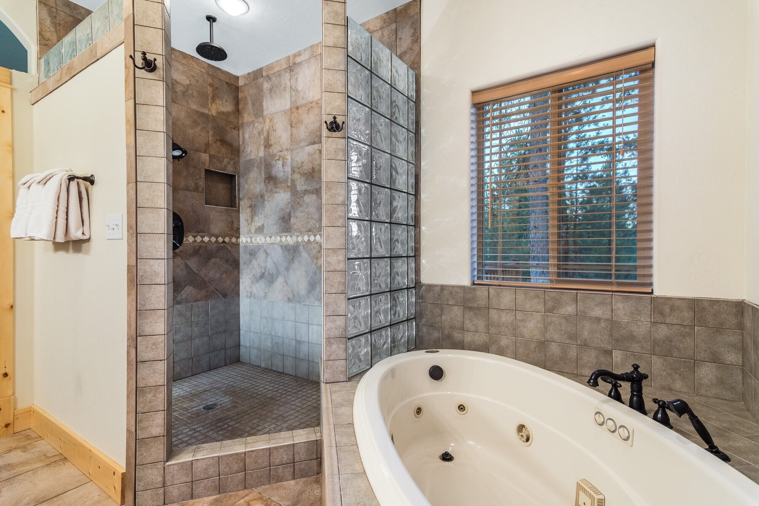 A bathroom with a walk-in shower, a bathtub, and a window with blinds.