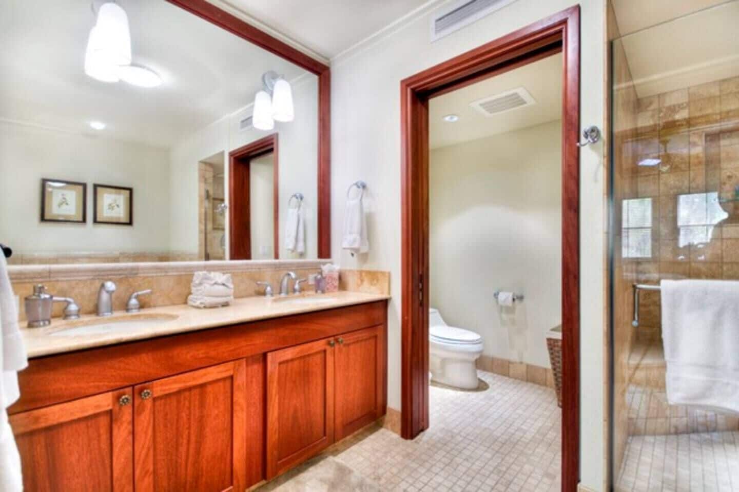 Un baño con tocador de madera, un espejo grande y cabina de ducha de vidrio.