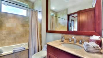 A bathroom with a bathtub, toilet, and vanity with a sink and mirror.
