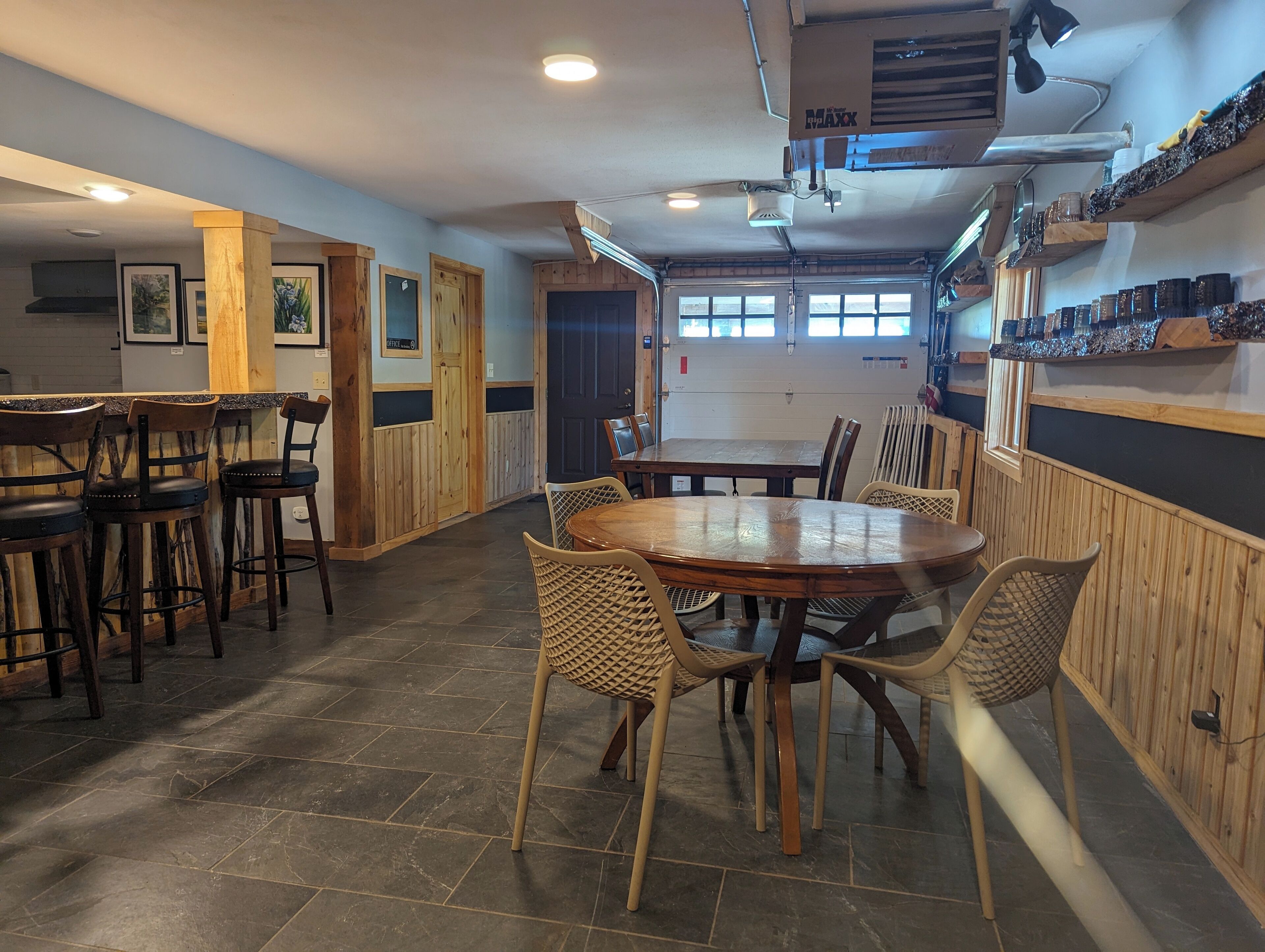 Un restaurante con interior de madera, una mesa central para comer y taburetes de bar.