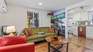 Een woonkamer met een groene bank, een rode stoel, een houten salontafel en een tv op een meubel.