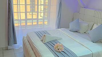 Un dormitorio con una cama grande, una ventana con cortinas y una lámpara de pared.
