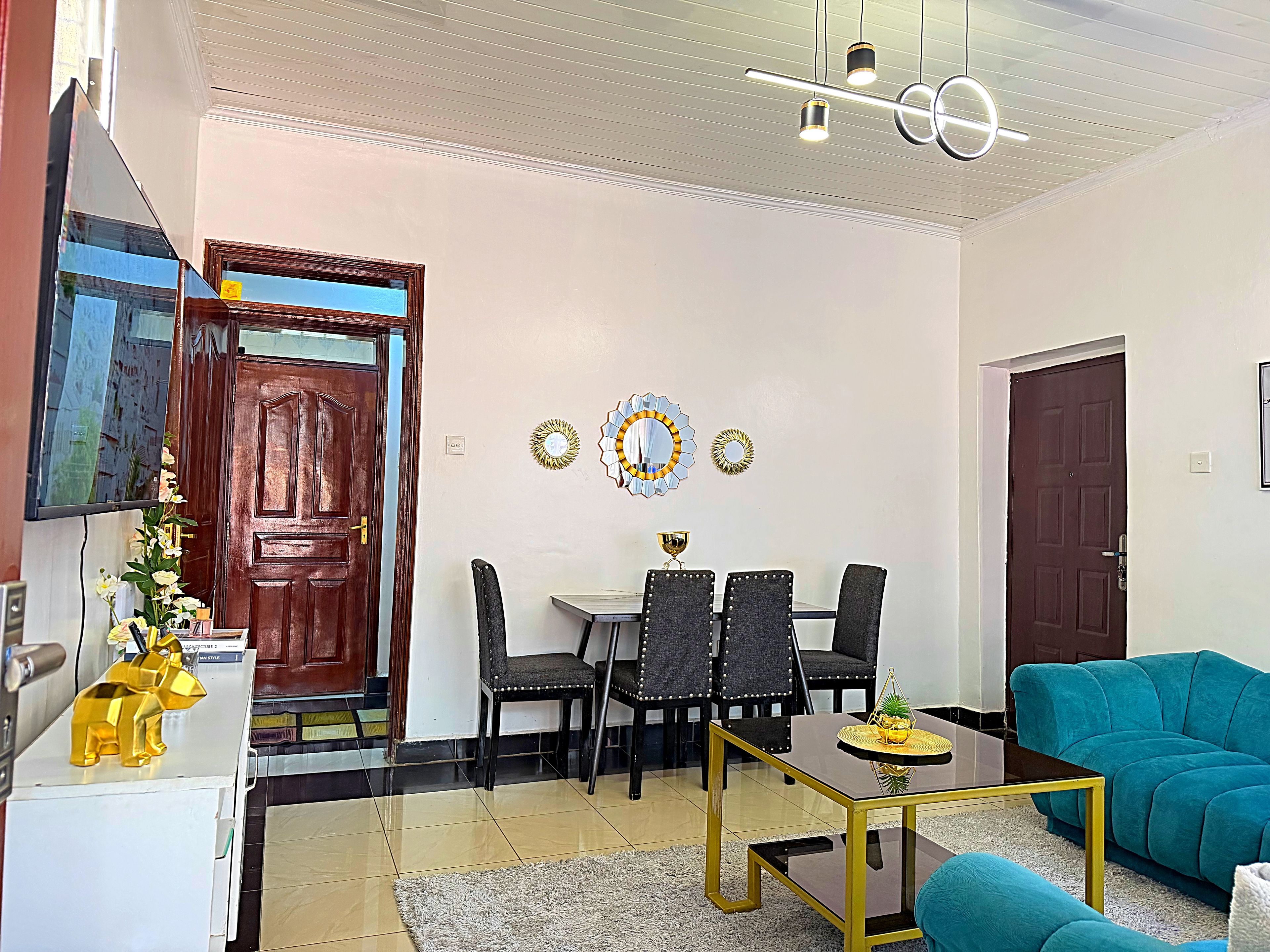 Un salon comprenant un canapé, une table basse, une table à manger avec des chaises, un téléviseur et une porte.