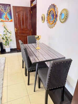 Un comedor con una mesa de madera y sillas tapizadas, una planta en maceta y decoración mural.