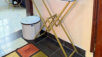 A room with a glass and metal console table, a round mirror, decorative plates, and a wicker basket.