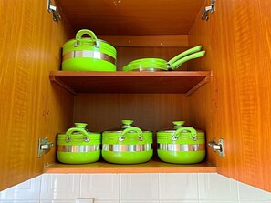 Ein Küchenschrank mit drei grünen Aufbewahrungsbehältern und einem grünen Geschirrset auf der oberen Ablagefläche.