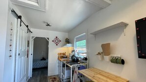 A compact kitchen with a wooden table, a sink, and a hanging pot rack. - Petite and Private Little Place (Lake Isabella)