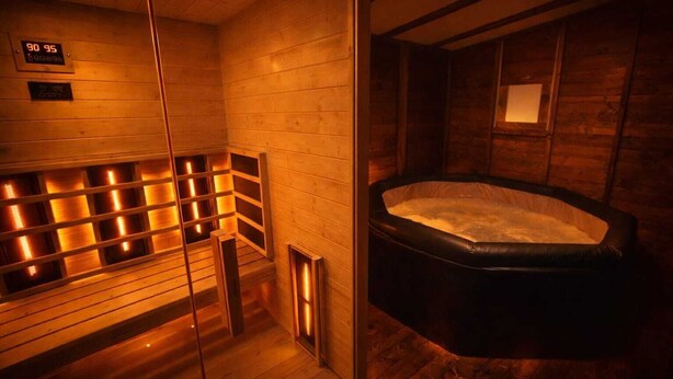 Un sauna aux murs en bois, doté d’une porte en verre et d’un banc chauffant.
