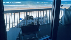Un balcón con vista a la playa, que incluye el océano y un cielo despejado.