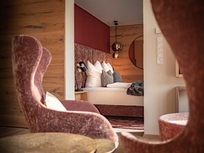 Une chambre à coucher moderne avec une tête de lit en bois, une table de chevet avec une lampe et un fauteuil confortable.