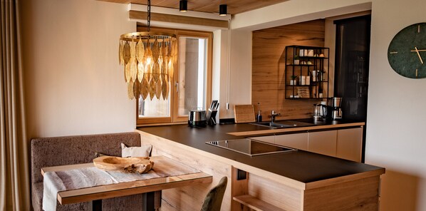 A modern kitchen with a wooden countertop, a built-in oven, and a hanging light fixture.