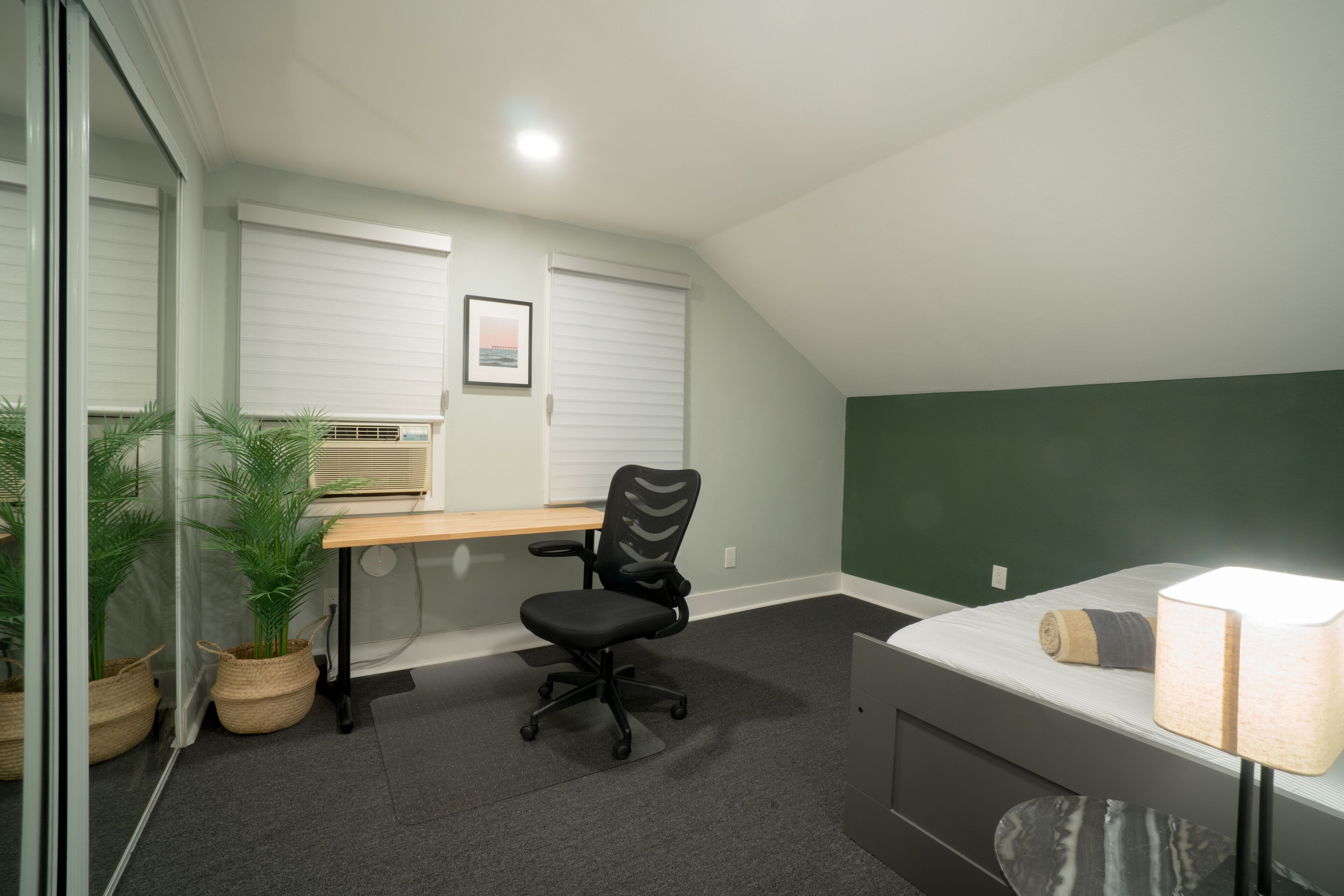 A small, private room with a desk, chair, and bed.
