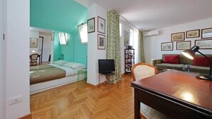 Ein gemütlicher Wohnraum mit Bett, Fernseher, Sofa und Esstisch.