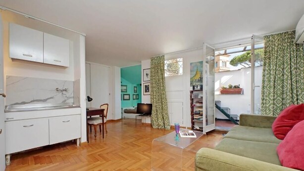 Ein Wohnzimmer mit Holzboden, einem grünen Sofa, einem Couchtisch und einem Fernseher.