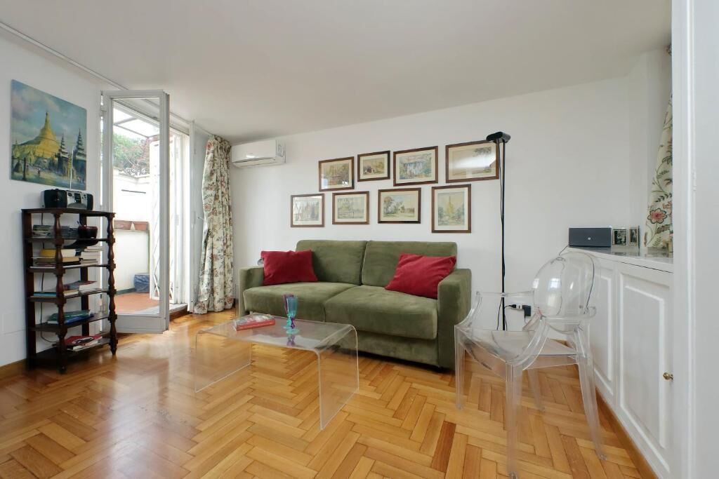 A living room with a green sofa, a coffee table, a bookshelf, and a painting on the wall.