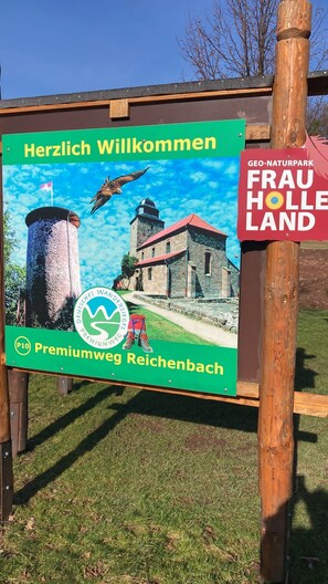 Une pancarte de bienvenue pour la région de Frau Holle, représentant un bâtiment traditionnel, un oiseau et des chaussures de randonnée.