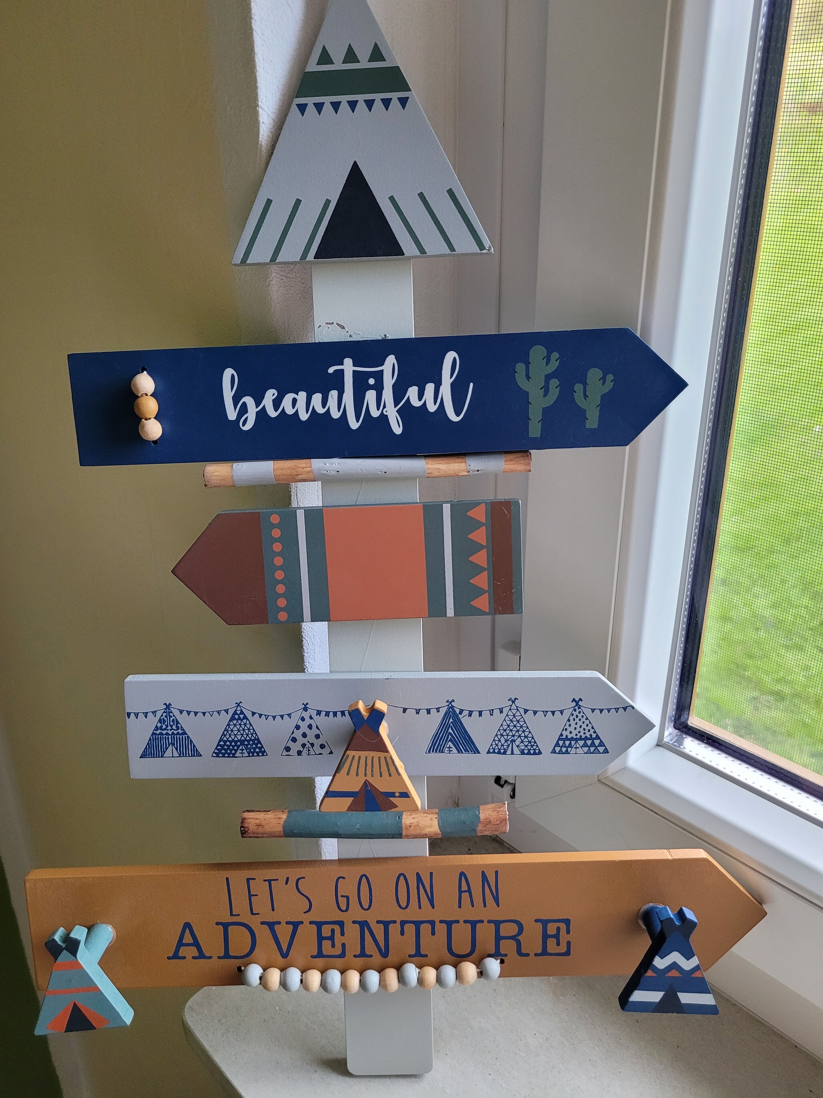 Una señal decorativa con las palabras “hermoso” y “vamos a vivir una aventura” sobre un alféizar.