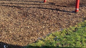 Un parque infantil con columpios rojos y una estructura de juegos de madera.