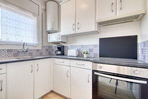 A kitchen with white cabinets, a microwave, a coffee maker, a toaster, and a stove.