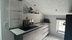 A compact kitchen with a built-in sink, wooden cabinets, and a window providing natural light.