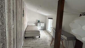 A bedroom with a bed, a desk, and a window.