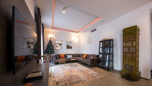 A modern living room with a sectional sofa, a coffee table, a large rug, and a bookshelf. - Beautiful peaceful villa with a pool in the center of Dubrovnik (Dubrovnik)