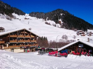 Une station de ski avec des bâtiments en bois, un télésiège et une montagne enneigée en toile de fond.