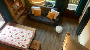 A cozy room with a sofa, a small round table, a wooden cabinet, and a hanging light fixture. - Arêches-Beaufort: Apt for 6-8, terrace, fully equipped, wi-fi and parking (Arêches-Beaufort)