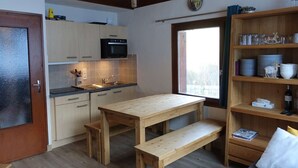 A compact kitchen with a wooden table, a bench, and a window with a view. - Arêches-Beaufort: Apt for 6-8, terrace, fully equipped, wi-fi and parking (Arêches-Beaufort)