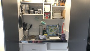 Een kleine keuken met een ingebouwde kookplaat, spoelbak en opbergladen.