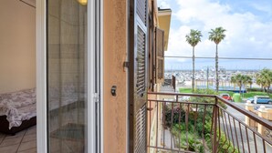 Un balcon avec vue sur une marina et des palmiers.
