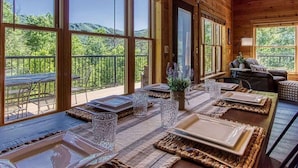 A dining area with a wooden interior, large windows, and a view of the outdoors. - …STUNNING Luxury 3BD Lodge! …HOT TUB/Games/VIEWS!… (Pigeon Forge)