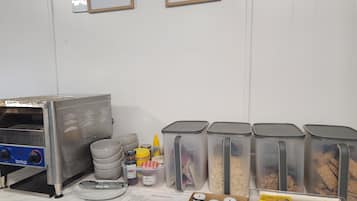 Uma área de cozinha com forno Birko, recipientes de armazenamento e um cardápio.
