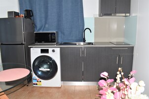 Cocina compacta con lavadora, microondas y lavamanos.