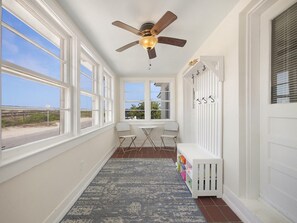 Enjoy the serene view from the large windows in this cozy hallway, featuring a ceiling fan and a convenient coat rack.