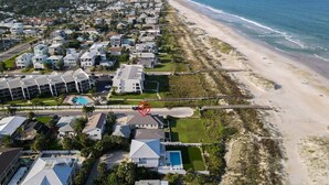 Vista aérea de una zona residencial costera con casas, una playa y un muelle.