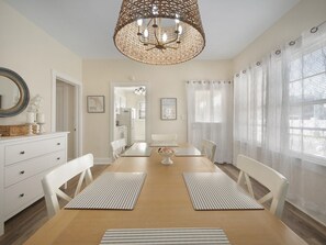 Enjoy meals in this elegant dining room with a central table, white chairs, and a woven chandelier.