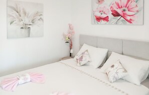 Une chambre à coucher avec un lit, des oreillers, une table de chevet et des œuvres d’art murales.