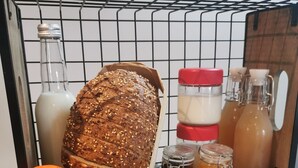 Un piano di lavoro in cucina con una pagnotta di pane integrale, una ciotola di arance, un piatto di pasticcini e diversi condimenti.