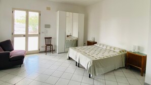 Un dormitorio con cama, una silla, armario y escritorio.