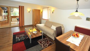 A modern living room with a sofa, coffee table, and dining table with fruit.