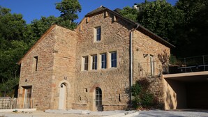 A stone building with a gabled roof, multiple windows, and a door.