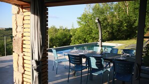 An outdoor patio with a pool, blue chairs, and a table set for dining.