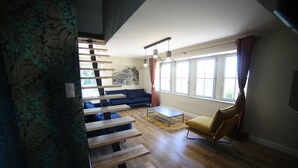 A modern living room with a staircase, a sofa, a chair, and a coffee table.